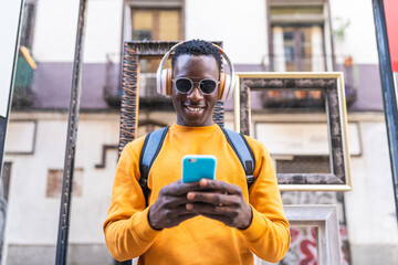 Wall Mural - Black Man Listening Music on Headphones Using Cellphone Outdoors.