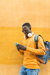 Wall Mural - Black Man Using Cellphone Wearing Yellow Sweater Outdoors.