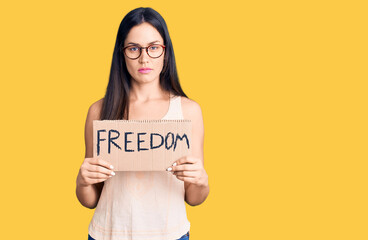 Poster - Young beautiful caucasian woman holding freedom banner thinking attitude and sober expression looking self confident