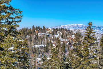 Canvas Print - Scenic sunny day view of a neighborhood in the midst of snowy mountain in winter