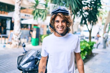 Young hispanic man smiling happy wearing moto helmet over motorcycle at the city