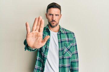 Wall Mural - Handsome man with beard wearing casual clothes doing stop sing with palm of the hand. warning expression with negative and serious gesture on the face.