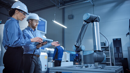 Poster - Factory Workshop: Professional Female Engineer, Male Machinery Operator Use Industrial Digital Tablet Computer to Work and Program Robot Arm for Production Line. High-Tech Facility with CNC Machines