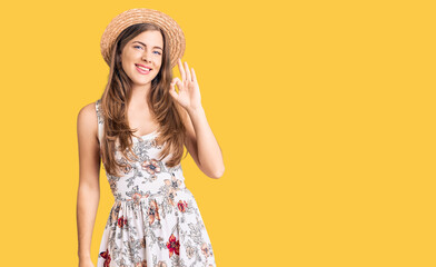 Wall Mural - Beautiful caucasian young woman wearing summer hat smiling positive doing ok sign with hand and fingers. successful expression.