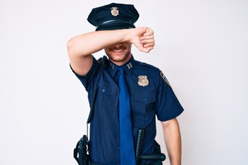 Wall Mural - Young caucasian man wearing police uniform covering eyes with arm smiling cheerful and funny. blind concept.