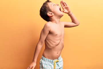 Wall Mural - Cute blond kid wearing swimwear shouting and screaming loud to side with hand on mouth. communication concept.