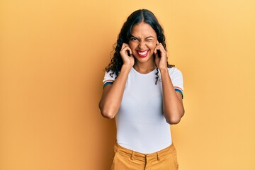 Poster - Young african american girl wearing casual clothes covering ears with fingers with annoyed expression for the noise of loud music. deaf concept.