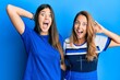 © Krakenimages.com - Hispanic family of mother and daughter wearing casual clothes over blue background crazy and scared with hands on head, afraid and surprised of shock with open mouth