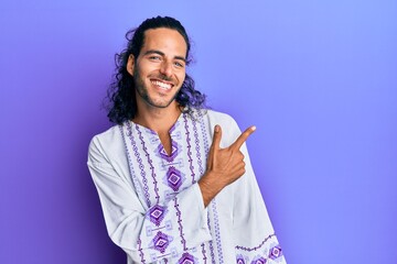 Sticker - Young handsome man with long hair wearing bohemian and hippie shirt cheerful with a smile of face pointing with hand and finger up to the side with happy and natural expression on face