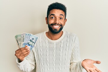 Poster - Handsome hispanic man with beard holding dollars celebrating achievement with happy smile and winner expression with raised hand