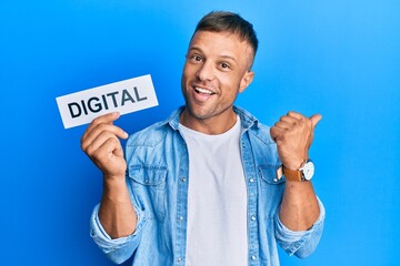 Canvas Print - Handsome muscle man holding digital word on paper pointing thumb up to the side smiling happy with open mouth