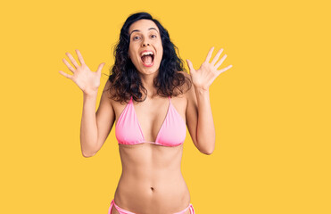 Wall Mural - Young beautiful hispanic woman wearing bikini celebrating crazy and amazed for success with arms raised and open eyes screaming excited. winner concept