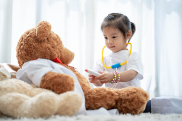 a happy asian girl smiling and lying on the floor with playing teddy bear