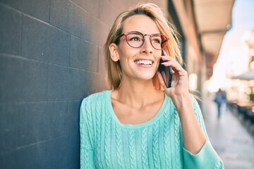 Young blonde woman smiling happy talking on the smartphone at the city.