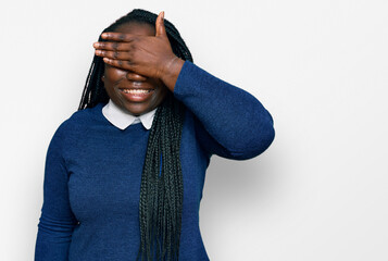 Poster - Young black woman with braids wearing casual clothes smiling and laughing with hand on face covering eyes for surprise. blind concept.