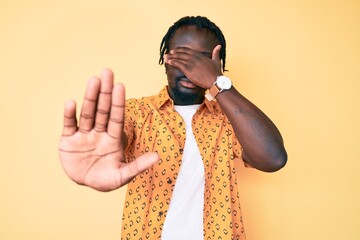 Canvas Print - Young african american man with braids wearing casual clothes covering eyes with hands and doing stop gesture with sad and fear expression. embarrassed and negative concept.