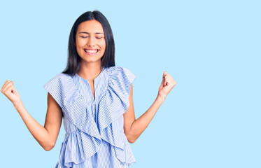 Sticker - Young beautiful latin girl wearing casual clothes very happy and excited doing winner gesture with arms raised, smiling and screaming for success. celebration concept.