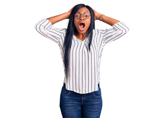 Poster - Young african american woman wearing casual clothes and glasses crazy and scared with hands on head, afraid and surprised of shock with open mouth