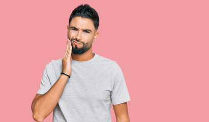 Canvas Print - Young man with beard wearing casual grey tshirt touching mouth with hand with painful expression because of toothache or dental illness on teeth. dentist