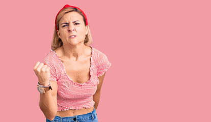 Poster - Young blonde woman wearing casual clothes and diadem angry and mad raising fist frustrated and furious while shouting with anger. rage and aggressive concept.