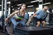 © ty - Fit couple doing jumping squats in crossfit gym.