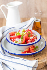 Fresh ripe juicy red tomato salad with green onions and vegetable oil.