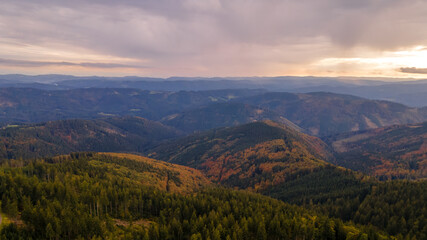 Wall Mural - Aerial view of the top of Lysa hill and its surroundings full of trees and views of the surrounding mountains during sunset.