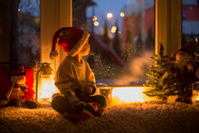 Cute Child, Sitting On A Window, Looking Outdoors For Santa Claus
