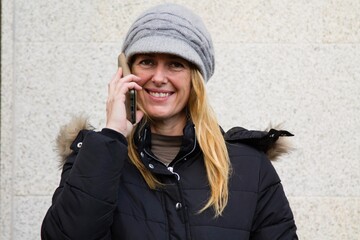 mature or middle-aged woman smiling with hat and mobile phone