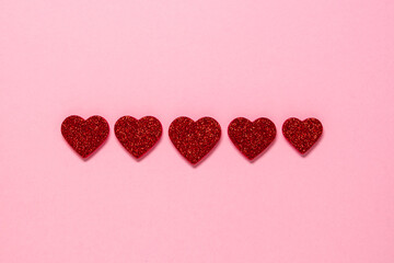 Five red shiny hearts love on a pink background. minimalism valentine's day romance, copy spase