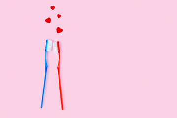 two toothbrushes of blue and red color and small hearts fly over them, a couple in love metaphor. re