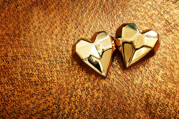 Wall Mural - Top view of two gold hearts over bronze background