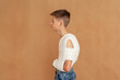 Boy with broken clavicle on beige background. Young man wears a plaster cast to fix the clavicle and immobilize the shoulder in case of a collarbone fracture.