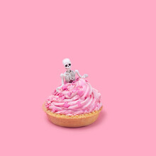 Skeleton With Sweet Cupcake On Pink Background. Romantic Holiday, Valentine's Day. Insulin Death, Sugar Addiction. Creative Unusual Minimal Concept. 