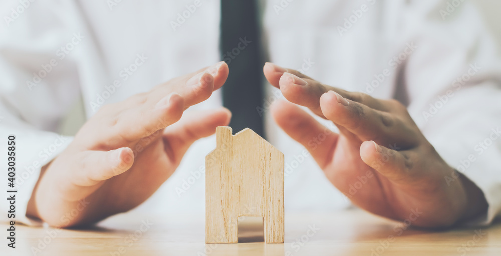 Insurance house and save money for property investment real estate concept. Man hands prevent wooden home - obrazy, fototapety, plakaty 