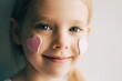 Close-up portrait of a girl wirh hearts on her face. Pink hearts on  cheeks. Valentines concept. Portrait of a blonde child. 