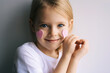 Pretty blonde girl show heart shape symbol with hands. Child and valentines day. Love. Pink hearts on a face.