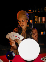 Wall Mural - Asian woman fortune teller using magical occult divine power crystal call to forecast luck on red table. 