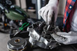 © LIGHTFIELD STUDIOS - partial view of technician in gloves examining disassembled motorbike gearbox