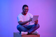 © Prostock-studio - Young black freelancer guy sitting with digital tablet under luminous neon light