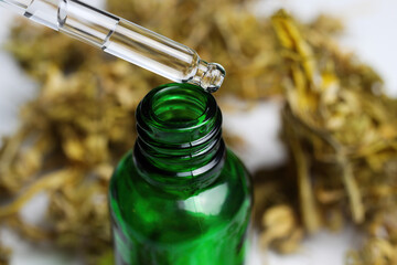 Macro close up of green isolated dropping pipette medical cannabinol cpd oil bottle with dried cannabis buds, white background