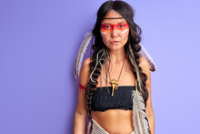 Woman In Indian Wearing And Colorful Makeup Posing At Camera, With Feathers On Head. Indigenous Peoples Of The Americas Outfit, Ethnic Woman