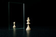 king is reflected in the mirror as a pawn on white background. underestimation of their abilities