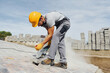 © standret - Uses circular saw. Male worker in yellow colored uniform have job with pavement