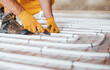 © standret - Close up view. Worker in yellow colored uniform installing underfloor heating system