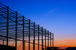 Silhouette low angle view of large industrial building structure in construction site area against colorful twilight sky background