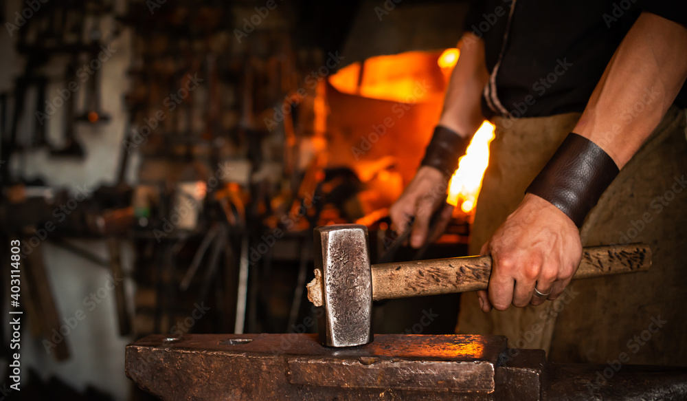 blacksmith performs the forging of hot glowing metal on the anvil - obrazy, fototapety, plakaty 