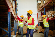 African Warehouse Worker Loading Delivery Boxes While Wearing Safety Mask - Focus On Face  