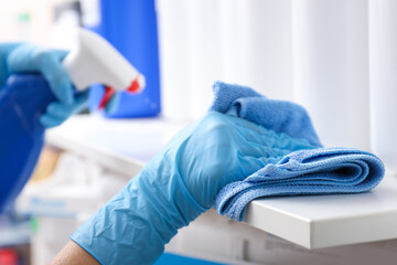 Woman cleaning shelf with rag and detergent in store, closeup