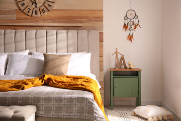 Beautiful dream catcher hanging near bed in stylish room interior